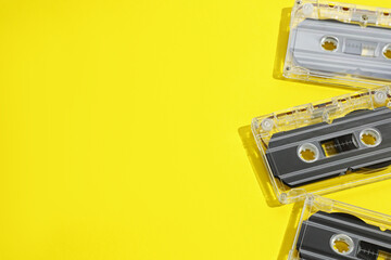 Fototapeta premium Audio cassettes with magnetic tapes on yellow background, above view. Space for text