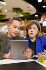 Gender diverse coworker business team eating salad and working digitally