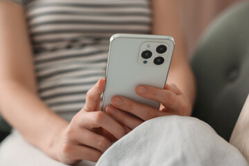 Woman using modern smartphone on sofa at home, closeup