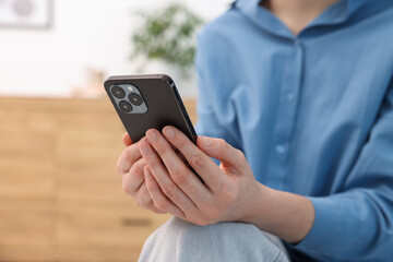 Woman using modern smartphone at home, closeup. Space for text