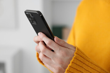 Woman using modern smartphone at home, closeup