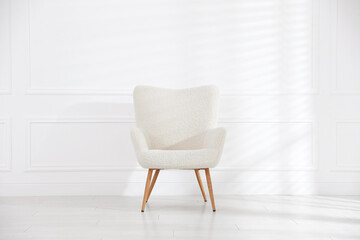 Comfortable beige armchair near white wall indoors