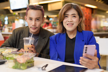 Gender diverse coworker business team eating salad and working digitally