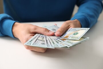 Man counting money at white table, closeup