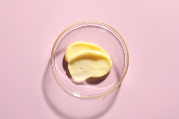 Cosmetic product in Petri dish on pink background, top view