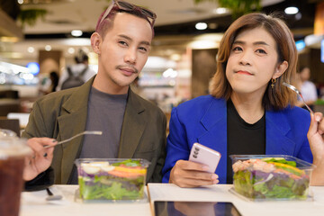 Gender diverse coworker business team eating salad and working digitally
