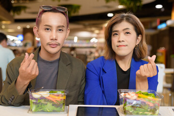 Gender diverse coworker business team eating salad and working digitally