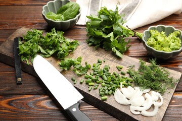 Different fresh herbs, spices and knife on wooden table, closeup