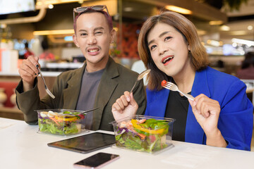 Gender diverse coworker business team eating salad and working digitally