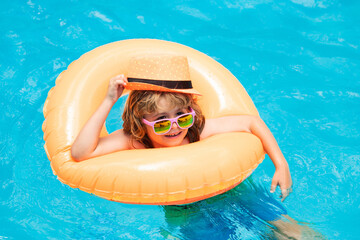 Child boy splashing in swimming pool. Swim water sport activity on summer vacation with children.