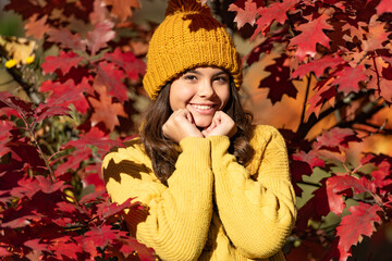 Teenager girl on autumn fall background. Portrait of kid in autumn fashion warm kids clothes. happy girl portrait in hat at autumn leaves on natural background