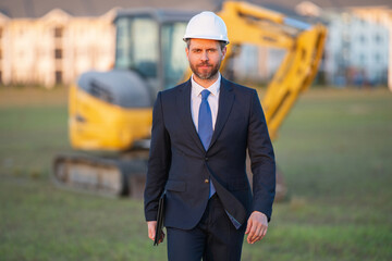 Construction owner near excavator. Confident construction owner in front of house. Architect, civil...