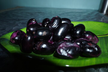 Smooth‑skinned, deep purple‑black round fruit with soft red or yellow flesh, sweet‑tart flavor, richly antioxidant and fiber‑packed