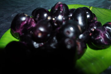 Smooth‑skinned, deep purple‑black round fruit with soft red or yellow flesh, sweet‑tart flavor, richly antioxidant and fiber‑packed