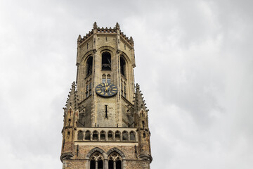 Clsoeup Bellfort tower (Halletoren) in front clouded sky in Brugge in Belgium