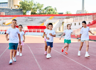 Young children having athletic exercise class running on the track, healthy lifestyle and children sport education concepts