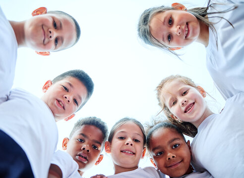 Group portrait of children team forming huddle, view from below. Sport, unity, togetherness, teamwork, healthy life concepts