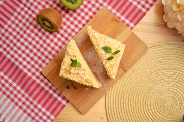 Kiwi and mint cheesecake slices on rustic wooden board with red checkered tablecloth