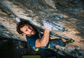 Strong man climbing on a mountain with safety equipment