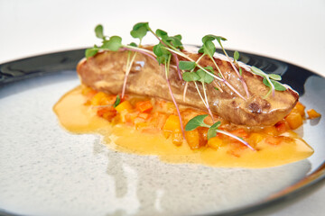 Gourmet seared fish dish with microgreens and citrus sauce on elegant plate