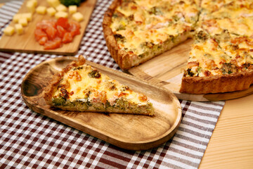 Delicious homemade vegetable quiche with cheese on wooden tray