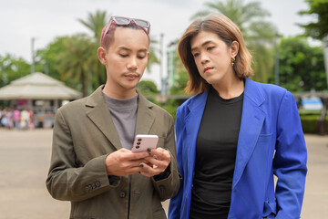 Gender diverse business coworker professionals using technology on city street