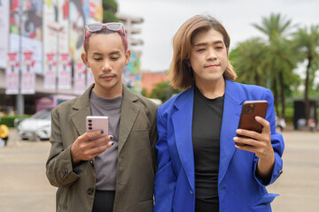 Gender diverse business coworker professionals using technology on city street