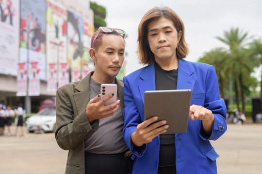 Gender diverse business coworker professionals using technology on city street