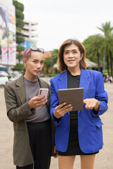 Gender diverse business coworker professionals using technology on city street