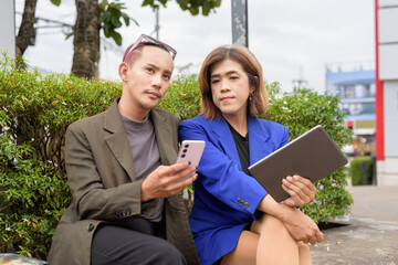 Gender diverse business coworker professionals using technology on city street