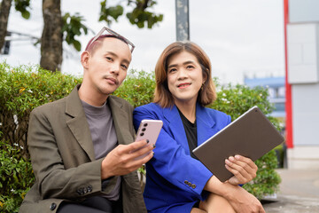 Gender diverse business coworker professionals using technology on city street