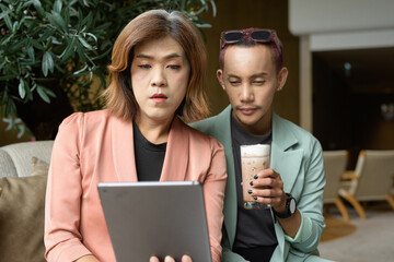 Transgender and non-binary coworkers working remotely in cafe