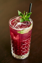 Refreshing iced berry cocktail with mint garnish in glass with straw