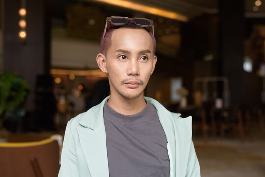 Non binary gay man with makeup sitting in cafe
