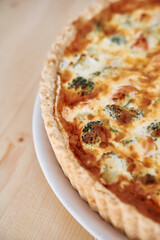 Savory broccoli and cheese quiche on white plate with crisp crust