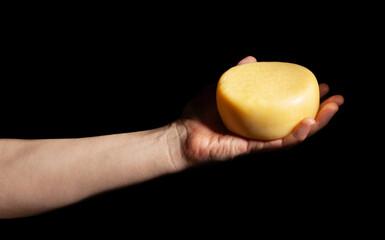wheel of cheese in hand on black background