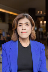 Confident Asian transgender woman in suit sitting alone in cafe