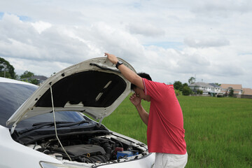 Depressed asian businessman is calling emergency help or car service center near broken car on road...