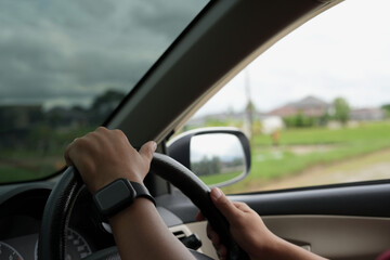 Close-up of the man's hand holding the steering wheel and looking for the fields and sunset, summer time and road trip for family leisure time.