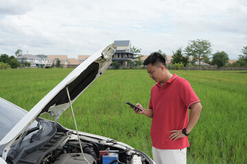 Depressed asian businessman is calling emergency help or car service center near broken car on road...
