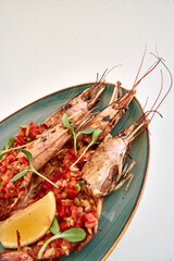 Grilled prawns with tomato salsa and lemon on oval plate