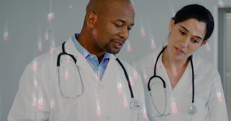 Reviewing data doctors wearing lab coats and stethoscopes in medical office, with binary overlay