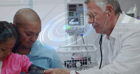 Doctor in white coat measuring girl's blood pressure at hospital ward, digital monitor, copy space