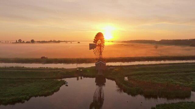 Fog-covered farmland with American-style windmill, drone capture Holland