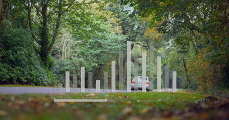 Showing silver sedan occupying frame on forest road, with faint bars and timeline slider overlay