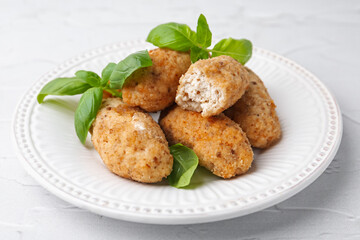 Tasty fried croquettes and basil on white textured table, closeup