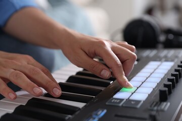 Woman working with MIDI keyboard indoors, closeup