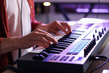 Man working with MIDI keyboard at table indoors, closeup
