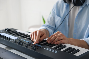 Man working with MIDI keyboard at table indoors, closeup