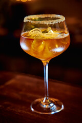 Elegant cocktail in glass with sugar rim sparkling on wooden table in dimly lit atmosphere